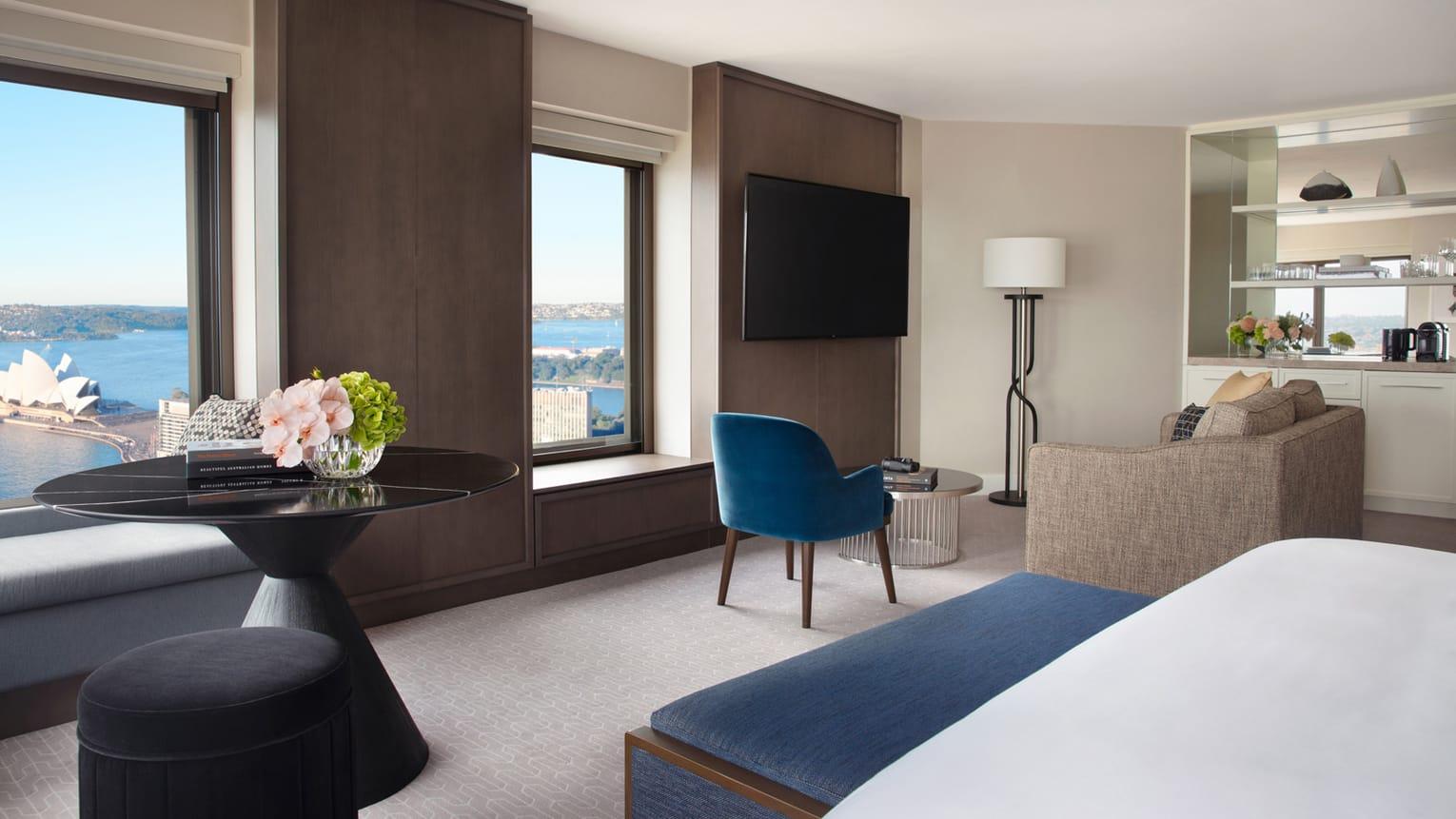 Four Seasons Hotel Sydney Kültér fotó The photo showcases a modern hotel room with a sleek and contemporary design. It features a large window that offers a view of the outside. The room includes:

- A comfortable seating area with a blue chair and a light-colored sofa.
- A round black t